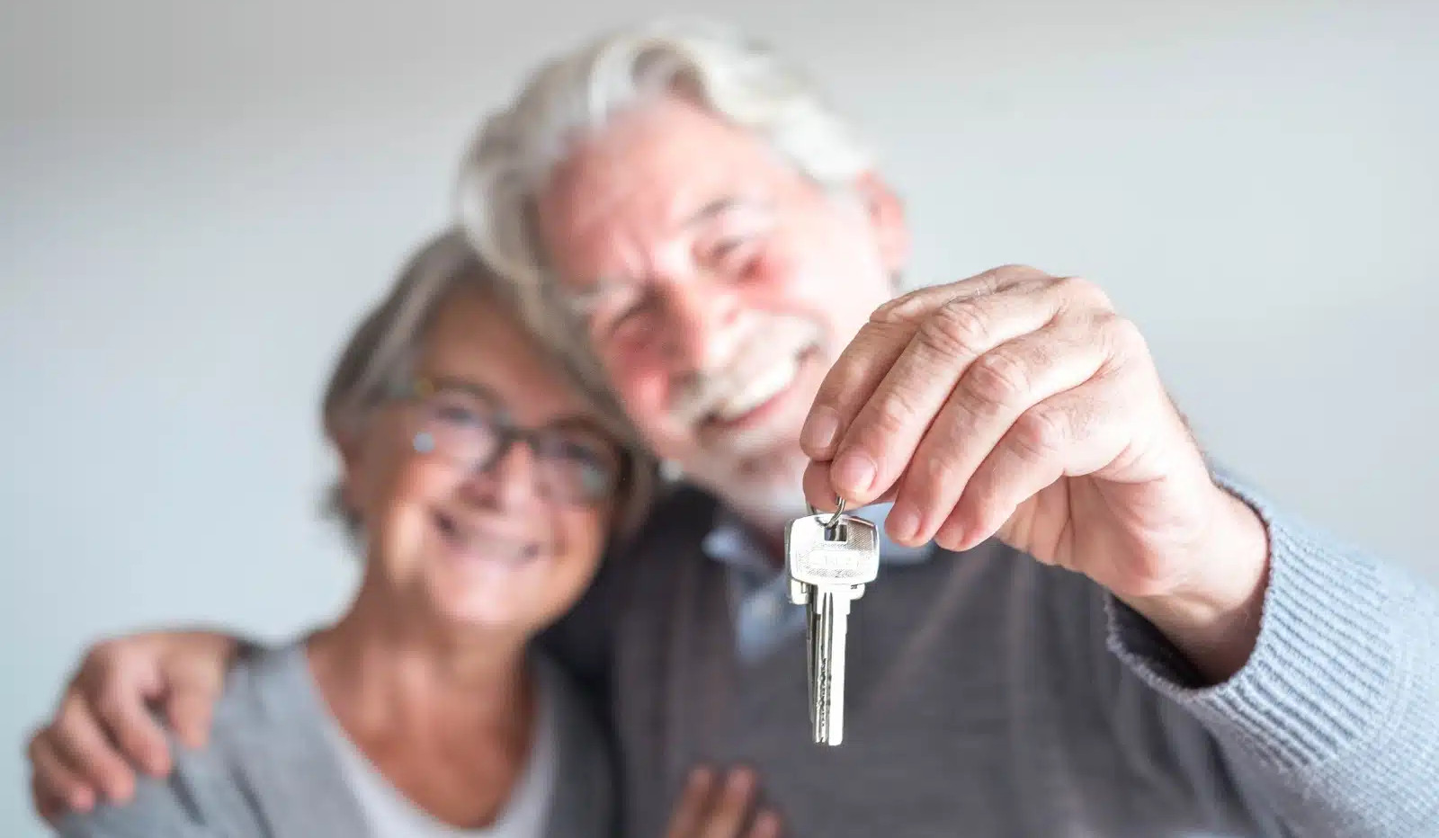 Glückliches älteres Ehepaar mit Hausschlüssel in der Hand