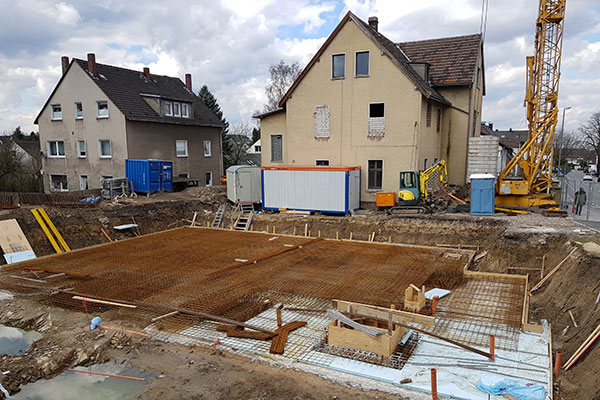 Baustelle eines Neubaus neben älteren Bestandsimmobilien